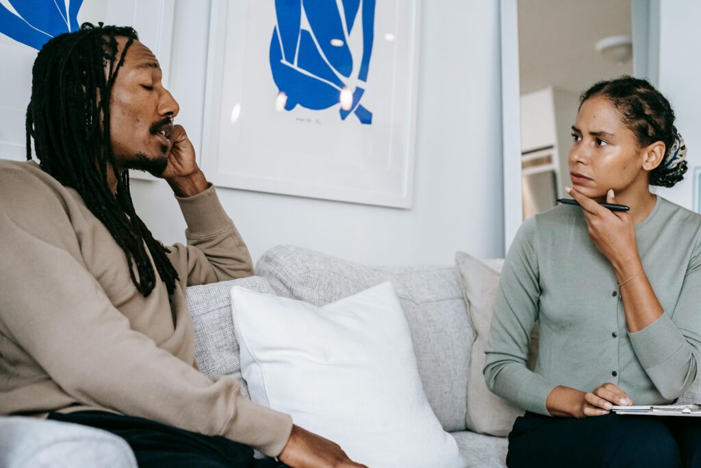 A focused therapy discussion between a male client and female therapist in a serene office.