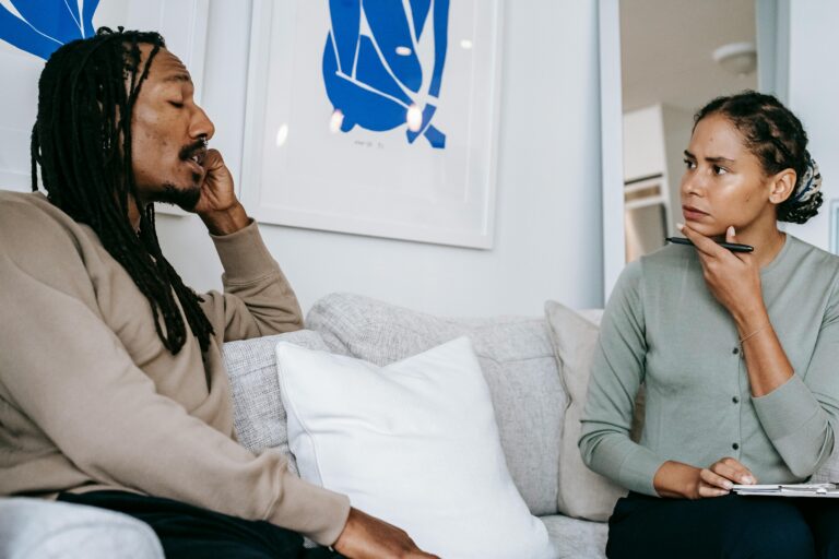 A focused therapy discussion between a male client and female therapist in a serene office.